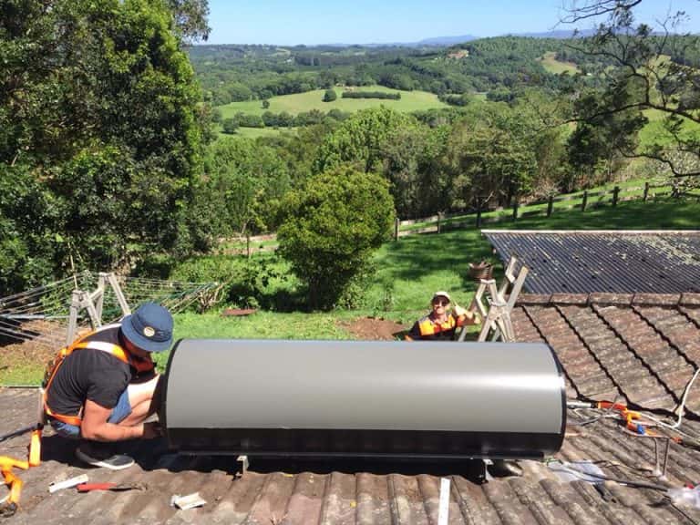 Plumbers installing solar hot water heater system on rooftop